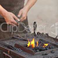 embers, fire, smoke, tools and the hands of a blacksmith