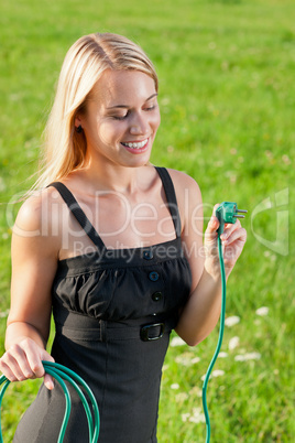 Green energy businesswoman hold plug sunny meadows