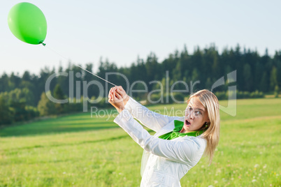 Happy young woman with green balloon meadows