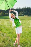 Happy young woman with green umbrella meadows