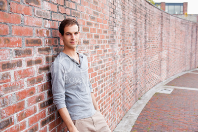 Male student leaning on a wall