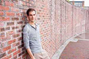 Male student leaning on a wall