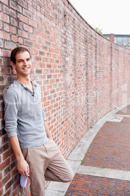 Portrait of a male student leaning on a wall