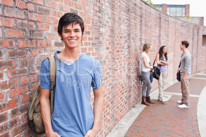 Male student posing while his friends are talking