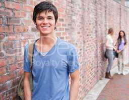 Handsome student posing while his friends are talking