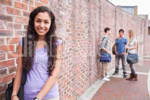 Smiling student posing while her friends are talking