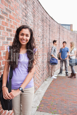 Portrait of a smiling student posing while her friends are talki