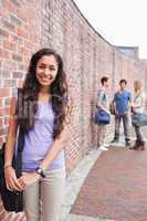 Portrait of a smiling student posing while her friends are talki