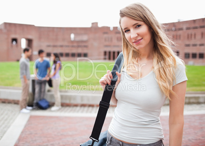 Blond-haired student posing while her friends are talking