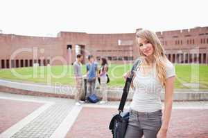 Blonde student posing while her friends are talking