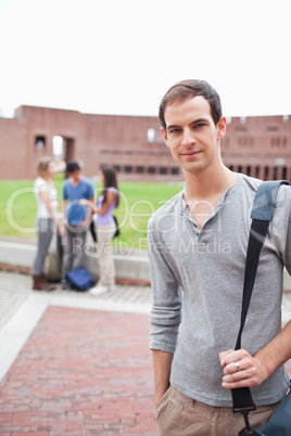 Portrait of a student posing while his classmates are talking