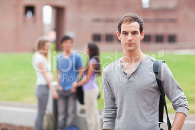 Male student posing while his classmates are talking