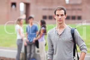 Male student posing while his classmates are talking