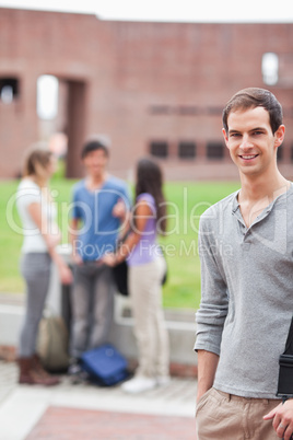 Portrait of a male student posing while his classmates are talki
