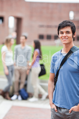 Portrait of a handsome student posing while his classmates are t
