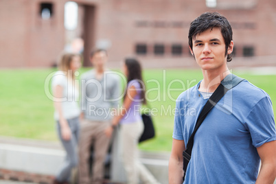 Handsome student posing while his classmates are talking