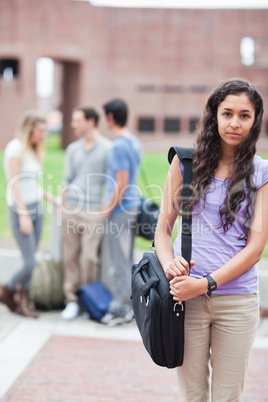 Portrait of a cute student posing while his classmates are talki