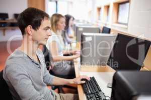 Serious male student working with a computer