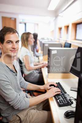 Portrait of a young male student posing with a computer