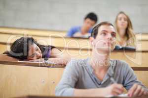 Students listening a lecturer while their classmate is sleeping