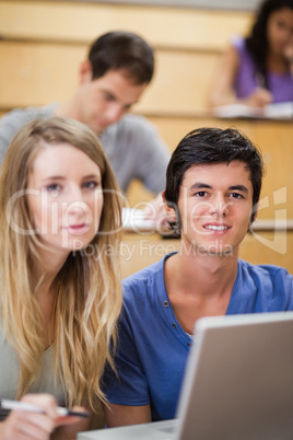 Portrait of young students posing with a laptop