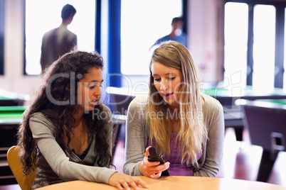 Young woman showing her mobile phone to a friend