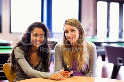 Cute friends posing with a mobile phone