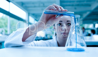 Scientist pouring a liquid in an Erlenmeyer flask with a test tu