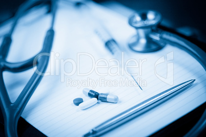 Note pad with stethoscope and pen along with  serynge and capsul