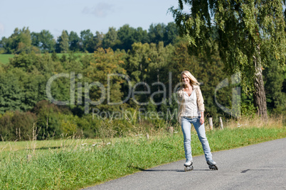 Inline skating young woman on sunny asphalt road