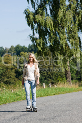 Inline skating young woman on sunny asphalt road