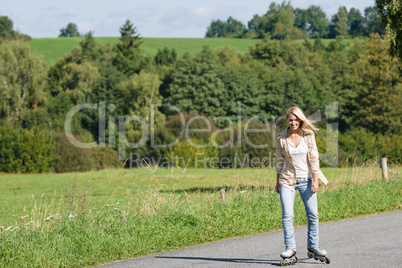 Inline skating young woman on sunny asphalt road