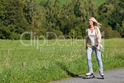 Inline skating young woman on sunny asphalt road