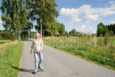 Inline skating young woman on sunny asphalt road