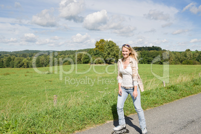 Inline skating young woman on sunny asphalt road