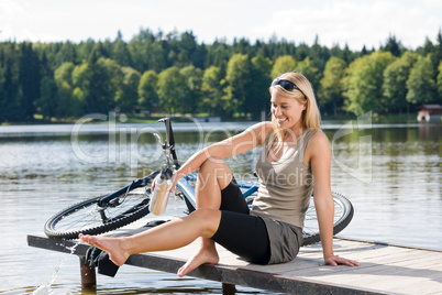 Sport biking young woman sitting by lake