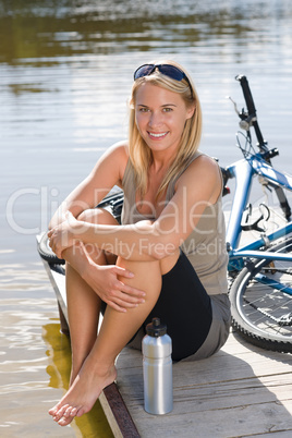 Sport biking young woman sitting by lake