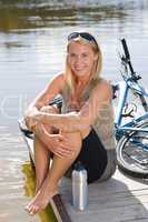 Sport biking young woman sitting by lake