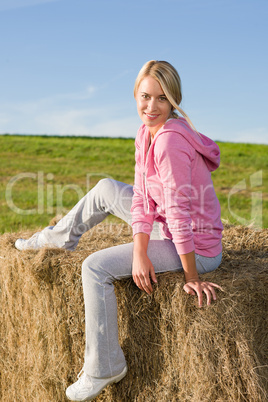 Sportive young woman relax on bales sunset