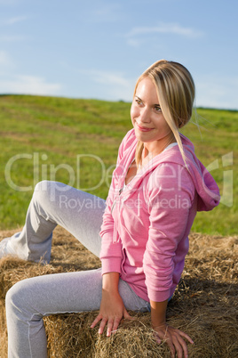 Sportive young woman relax on bales sunset