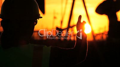 Female Engineer in Silhouette at Oil Production Site