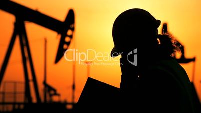 Engineer Oil Drilling in Silhouette at Sunset