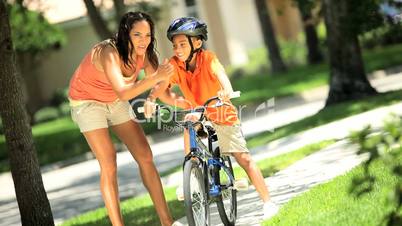 Young Ethnic Mother Encouraging Son on Bicycle