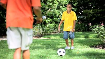 Ethnic Father & Son Kicking a Ball Together