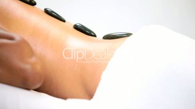 Female Ethnic Spa Client Relaxing with Hot Stone Therapy
