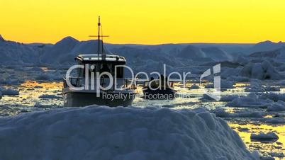 Nautical vessel at sunset in ice floes with icebergs