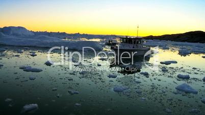 Nautical vessel at sunset in ice floes with icebergs