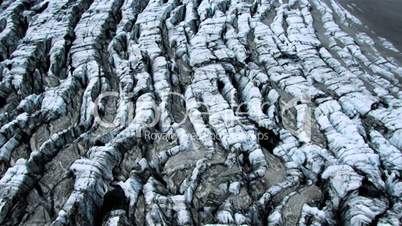 Aerial view of blue ice crevices covered in black volcanic ash, Iceland