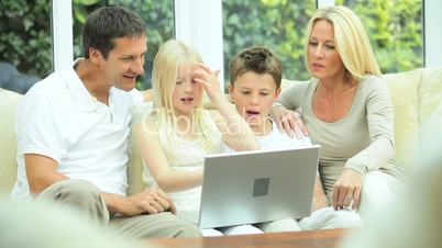 Young Caucasian Family Using Laptop on Sofa