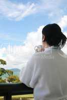 Professional businesswoman with a bath dress holding coffee cup looking thoughtful in a beautiful landscape